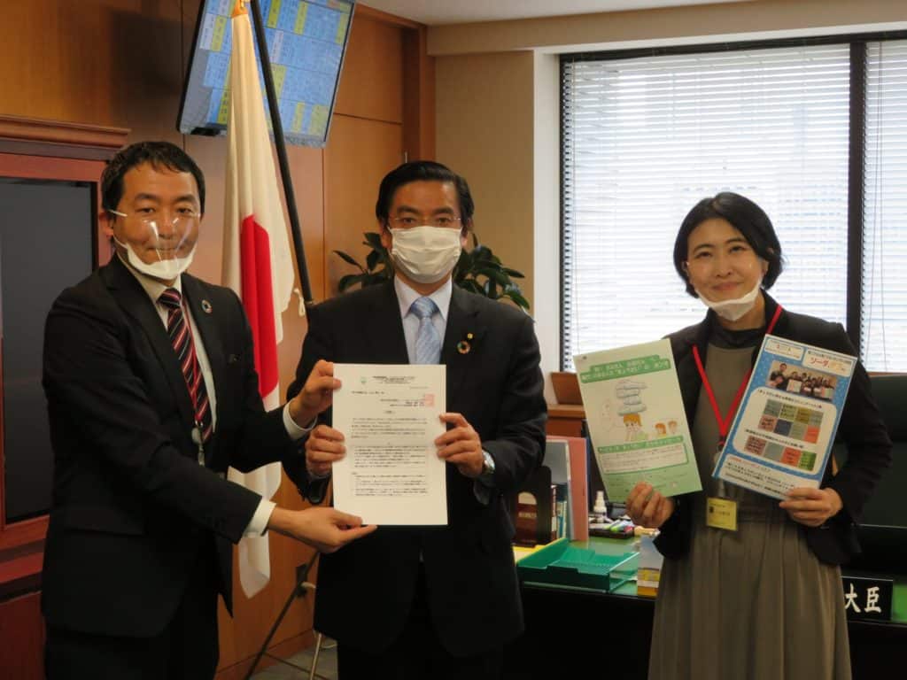 山本厚生労働副大臣(中央)に提言書を提出する伊藤理事長(左)と藤木家族プロジェクト担当理事(右)