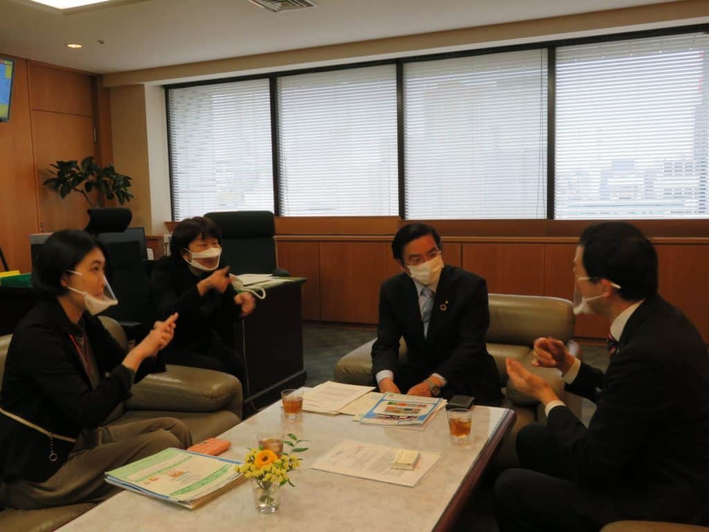 山本厚生労働副大臣(中央)と会話する伊藤理事長(右)と藤木家族プロジェクト担当理事(左)