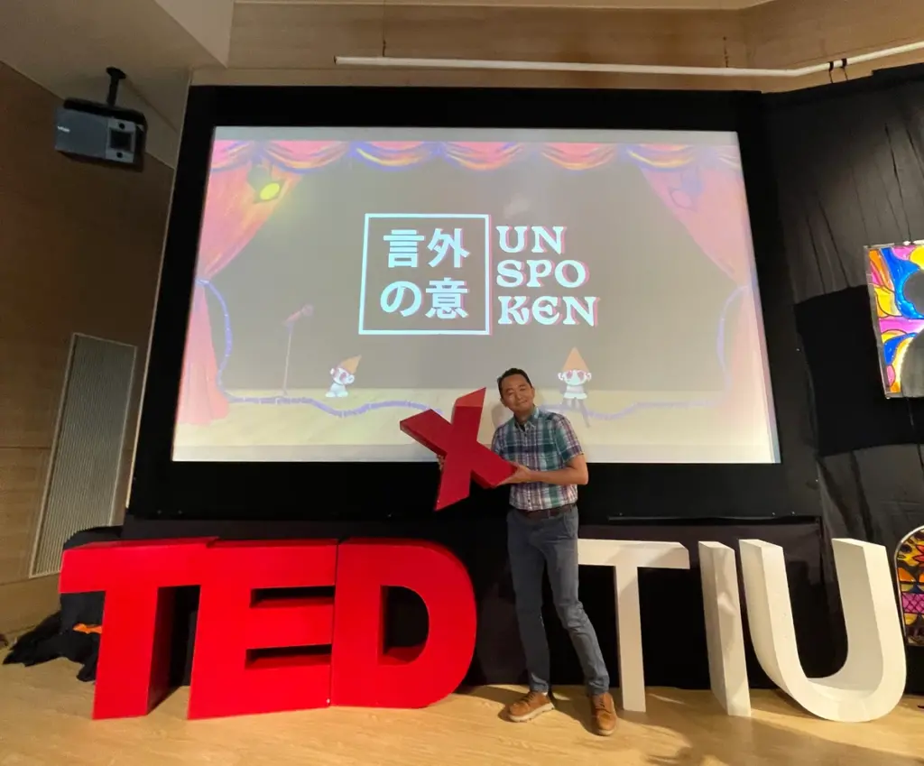 TEDｘTIUのキービジュアルの前で撮影する伊藤理事長