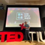 TEDｘTIUのキービジュアルの前で撮影する伊藤理事長